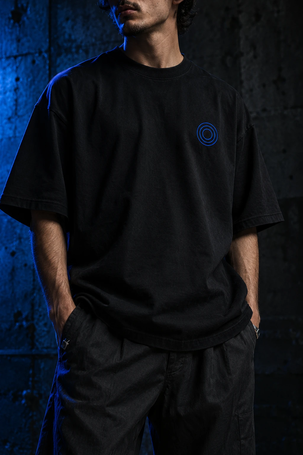 Streetwear campaign concept: oversized black tee with an electric-blue ripple emblem
